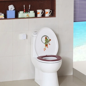 Creative 3D green frog sticker applied to the inner side of a white toilet lid in bathroom