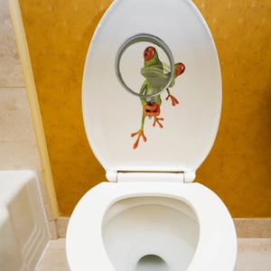 Close-up of a funny 3D green tree frog sticker with magnifying glass on toilet lid