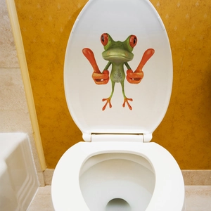Detail of 3D cartoon frog sticker with thumbs up gesture on a white toilet lid