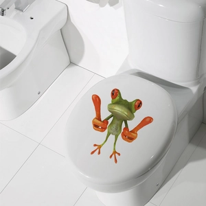 Detailed view of a 3D cartoon frog sticker applied on a white modern toilet lid