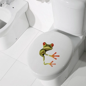 3D vivid green tree frog wall sticker with red eyes applied on a white toilet lid cover