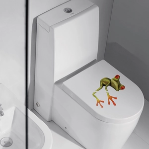 Detailed view of 3D green tree frog sticker with red eyes on a white toilet lid