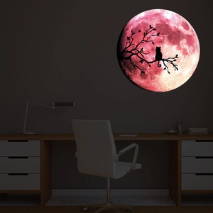 Sticker mural lumineux montrant une lune rose avec une silhouette de chat au mur