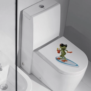Funny surfing frog sticker applied to a white ceramic toilet lid in a modern bathroom