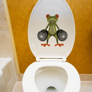 Funny green frog lifting weights cartoon sticker detail on a white ceramic toilet lid