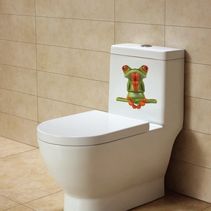 Detail of creative green frog sticker in meditation pose on a modern white toilet tank
