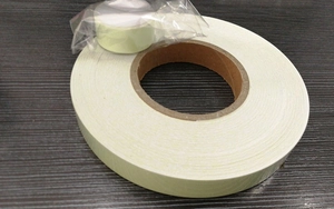 Luminous tape rolls on a dark wooden surface showing inner cardboard core and packaging