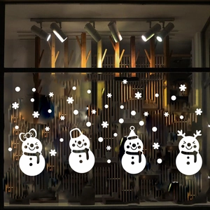 Close-up of white Christmas window stickers featuring cartoon snowmen and delicate snowflakes