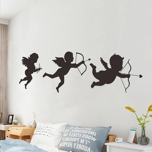 Three black Cupid silhouette wall stickers for Valentine's Day decor above a bed