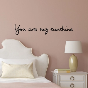 Detail of black handwritten 'You are my sunshine' wall sticker in a bedroom setting