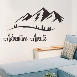 Adventure Awaits mountain wall decal stickers with trees over a blue sofa in a room