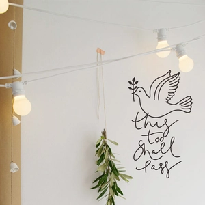 Wall decal detail showing a black peace dove with olive branch and this too shall pass text