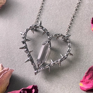 Gothic thorns heart necklace with purple crystal pendant on a grey textured background