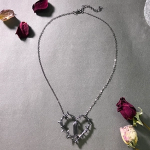 Gothic thorns heart pendant with dark crystal prism on a black chain with rose petals