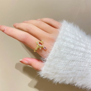 Detailed view of pink zircon star ring with gold finish on a model wearing fuzzy top