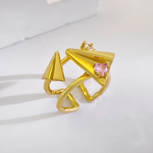 Detailed view of paper plane ring with pink heart zircons on a wavy gold band