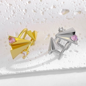 Macro shot of gold and silver paper plane rings with pink heart zircons on white stone