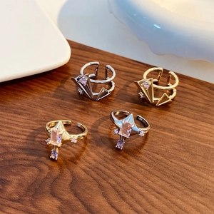 Detail view of pink zircon star rings and geometric designs on dark wood background