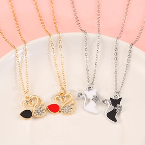 Detailed view of swan and cat enamel pendants with rhinestone accents on chains