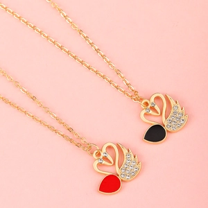 Close-up of gold swan pendant necklaces with red and black enamel and sparkling rhinestones