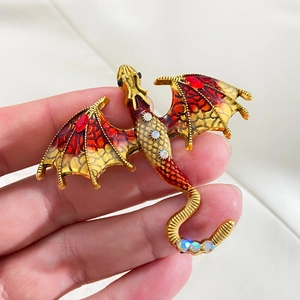 Vintage dragon brooch in gold-tone alloy with red enamel wings and sparkling rhinestones