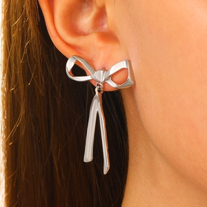 Close-up of elegant silver bow earrings with long streamers worn by a model