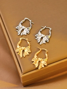 Detailed view of gold and silver bow-shaped hoop earrings with heart centers on display