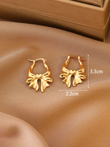 Golden bow heart earrings with dimensions 3.3cm by 2.2cm on brown silk background