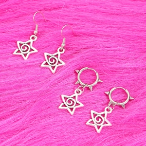 Set di orecchini a stella gotici argentati con borchie e ciondoli punk su fondo rosa