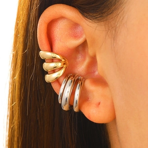 Detail of layered gold and silver ear cuffs showing triple-line metallic texture
