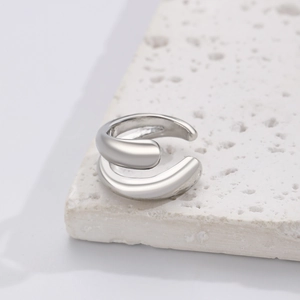 Close-up of a silver streamlined ear cuff with a polished finish on a stone surface