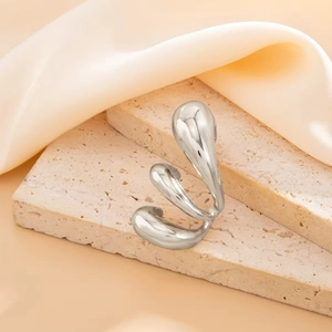 Macro shot of liquid metal silver ring with irregular wavy design on silk fabric