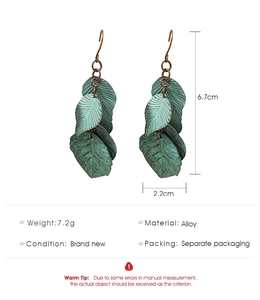 Detail view of vintage green metal leaf earrings with size dimensions and hook design