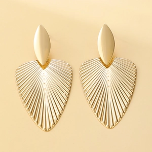 Close-up of golden fan-shaped leaf earrings with radiating metal texture and vintage style