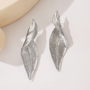 Detailed close-up of silver-toned metal earrings featuring twisted leaf texture and design