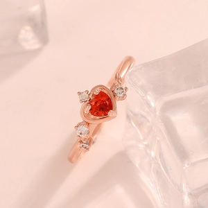 Nahaufnahme eines herzförmigen roten Edelsteinrings in Roségold mit Zirkon-Akzenten