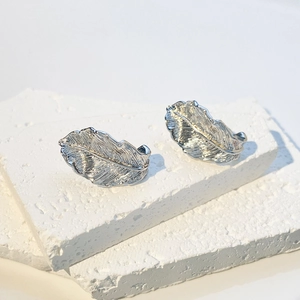 Macro detail of silver feather earrings showing intricate textures on stone surface