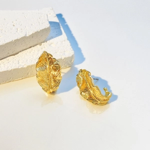 Detailed close-up of golden leaf earrings showing delicate brushed texture and elegant metallic finish