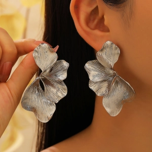 Detail of silver petal earrings showing large brushed metal texture on earlobe