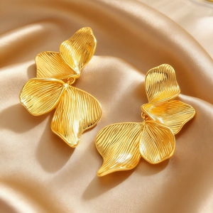 Close-up of golden petal earrings with delicate brushed texture on silk fabric