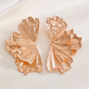 Macro shot of gold ginkgo leaf earrings featuring detailed pleated metal texture