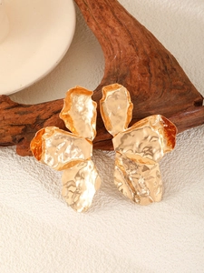Detailed macro view of gold-tone hammered metal flower earrings with vintage leaf pattern
