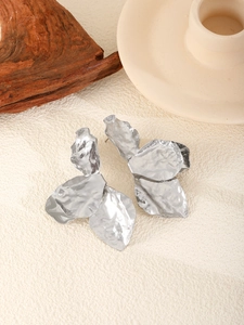 Detail of silver irregular metal leaf earrings with abstract crumpled texture on a minimalist base