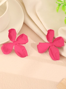Detail view of pink petal earrings with matte finish on a textured background