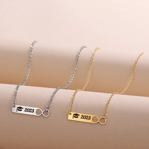 Close-up of gold and silver graduation necklaces with infinity symbol and 2023 charms