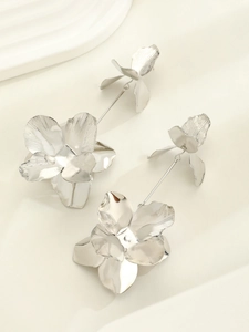 Macro shot of silver oversized floral earrings featuring hammered metal texture and artful design