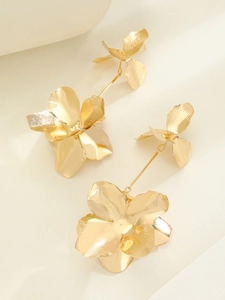 Detailed macro view of golden flower drop earrings with textured brushed metal petals