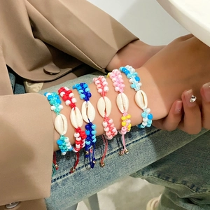 Detail von bunten handgemachten Boho-Perlenarmbändern mit Kauri-Muschel am Handgelenk