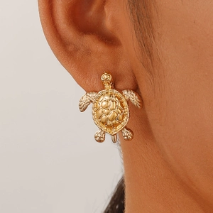 Detailed close-up of a gold turtle stud earring featuring intricate 3D shell textures