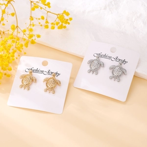 Elegant sea turtle stud earrings in gold and silver finish on jewelry display card